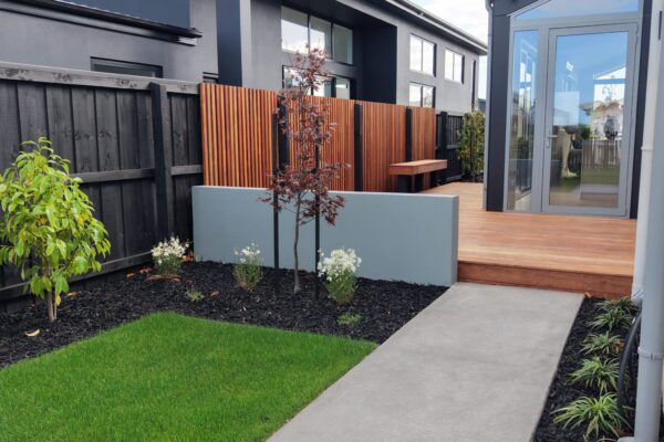 Modern new build garden with timber deck, concrete path, lawn and privacy screening