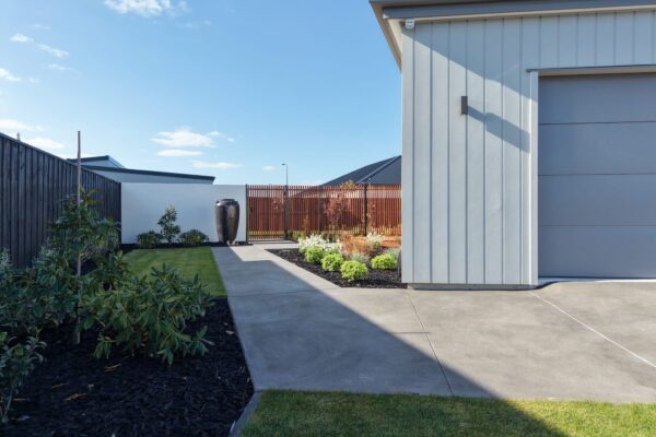 Contemporary home exterior with concrete driveway, lawn, garden planting and timber screen fence