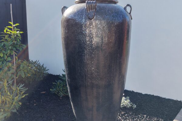 Close up of a large feature urn in a modern garden bed with black mulch
